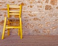 Vintage yellow chair on stone wall background Royalty Free Stock Photo