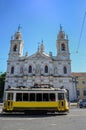 Vintage yellow tram and the Estrela Basilica or Royal Basilica and Convent of the Most Sacred Heart of Jesus, in Lisbon,
