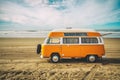 Vintage yellow van on the beach with cloudy sky on background, retro color effect, vacations concept Royalty Free Stock Photo