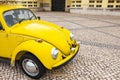 Vintage yellow Volkswagen beetle car on a cobblestone road in Portugal Royalty Free Stock Photo