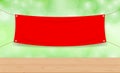 Vinyl blank red on green bokeh background and wood plank table, mock up textile fabric empty for banner advertising stand hanging Royalty Free Stock Photo