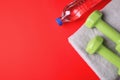 Vinyl dumbbells, towel and bottle of water on color background, flat lay