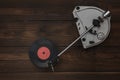 A vinyl record player and a red disc on a wooden table. Royalty Free Stock Photo