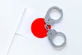 Violation of law, law-breaking concept. Metal handcuffs on Japaniese flag on white background top view