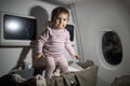 Violation of safety rules in an airplane. danger. cute little toddler jumping in baby bassinet during the flight