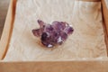 Violet amethyst crystal in a kraft paper box on wooden background. Top view. Copy, empty space for text Royalty Free Stock Photo