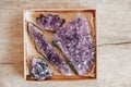 Violet amethyst crystals in a kraft paper box on wooden background. Top view. Copy, empty space for text