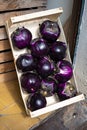 Violet Aubergines for sale in a wooden box, purple round eggplant