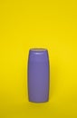 Violet blank unbranded cosmetic plastic bottle for shampoo, gel, lotion, cream, bath foam yellow background. Royalty Free Stock Photo