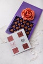 Violet box of heart shaped chocolates, postcard and fabric rose flower on white background. Valentines day 14 February sweet Royalty Free Stock Photo