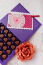 Violet box of heart shaped chocolates, postcard and fabric rose flower on white background. Valentines day 14 February sweet Royalty Free Stock Photo