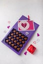 Violet box of heart shaped chocolates, postcard, red candle on white background. Valentines day 14 February sweet present Royalty Free Stock Photo