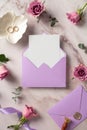 Violet envelope with blank paper card, golden rings, roses flowers on marble background. Wedding stationery set, top view Royalty Free Stock Photo