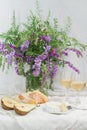 Violet flowers, pears, brie cheese and wine glasses. Still life