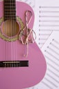 Violet guitar for children with treble clef on music sheets back