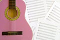 Violet guitar for children with treble clef on music sheets back