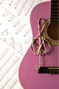 Violet guitar for children with treble clef on music sheets back