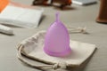 Violet menstrual cup with cotton bag on white table Royalty Free Stock Photo