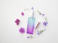 Violet perfume bottle with flowers around. lavender and spring flower aroma, aromatherapy, spa concept, skin care Royalty Free Stock Photo