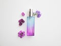 Violet perfume bottle with flowers around. lavender and spring flower aroma, aromatherapy, spa concept, skin care Royalty Free Stock Photo