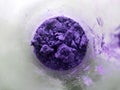 Violet powder in glass cup, bowl with ingredient close up. colored granules in transparent container. Magic fantasy powder.