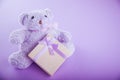 Teddy bear with a gift box for Valentines day on purple background Royalty Free Stock Photo