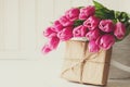 Violet tulips bouquet in basket in front of white wooden wall.