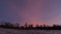 Violet winter skies after sunset above field and line of trees under Low Tatras mountains