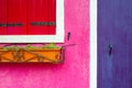 Violet wooden door, window with red shutters and pink wall Royalty Free Stock Photo