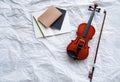 Violin and bow put beside opened book and pencil,on grunge surface background Royalty Free Stock Photo