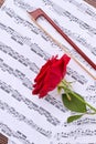 Violin bow and rose on music sheets.