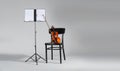 Violin, chair and note stand with music sheets on grey background. Royalty Free Stock Photo