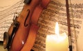 Violin on music sheet behind a candle