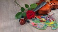 Violin, red rose, colorful palette and brush on a wooden table. copy space