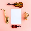 Violin, saxophone, double bass, horn and white mockup blank on pink background, top view. Copy Royalty Free Stock Photo