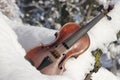 Violin on snow. Old brown wooden violin with 4 strings is outside outdoors on white cold snow when sun is shining