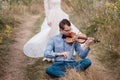 Violinist and woman in white dress , young man plays on the violin the background nature Royalty Free Stock Photo