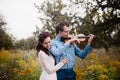 Violinist and woman in white dress , young man plays on the violin the background nature Royalty Free Stock Photo