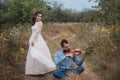 Violinist and woman in white dress , young man plays on the violin the background nature Royalty Free Stock Photo