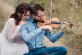 Violinist and woman in white dress , young man plays on the violin the background nature