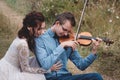 Violinist and woman in white dress , young man plays on the violin the background nature