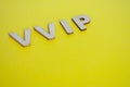 VIP wooden letters representing Very Very Important People on yellow background