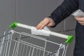 Viral disease prevention concept. Man wipes down a handle of public shopping cart with a disinfecting moist towelette in mall or Royalty Free Stock Photo