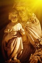 Virgin Mary with Jesus Christ in sunlight. Ancient statue. Selective focus on faces