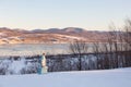 Virgin Mary statue seen in snowy field with the St. Lawrence River and the Laurentian mountains in the bac
