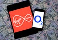 Virgin Media and O2 Telefonica logos on the mobile devices placed on dollars. Concept for potential multibillion merger of the two