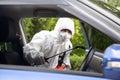 Virologist man wearing PPE kits kills bacteria and viruses inside the car.