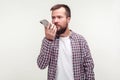Virtual assistant. Portrait of serious bearded man talking to mobile phone using voice application. white background
