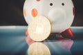 Golden bitcoin on and piggy bank over gently lit dark background and light ray Royalty Free Stock Photo