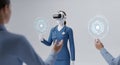Virtual Healthcare Assistant in VR Headset Interacting with Holographic Interface with Doctors in Blur on Plain Background Royalty Free Stock Photo